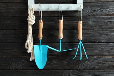 Photo of Set of professional gardening tools hanging on wooden wall