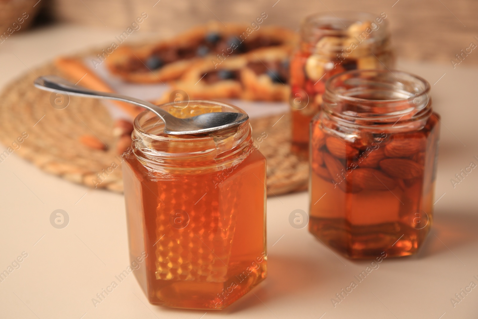 Photo of Jars with nuts and honey on beige table, space for text