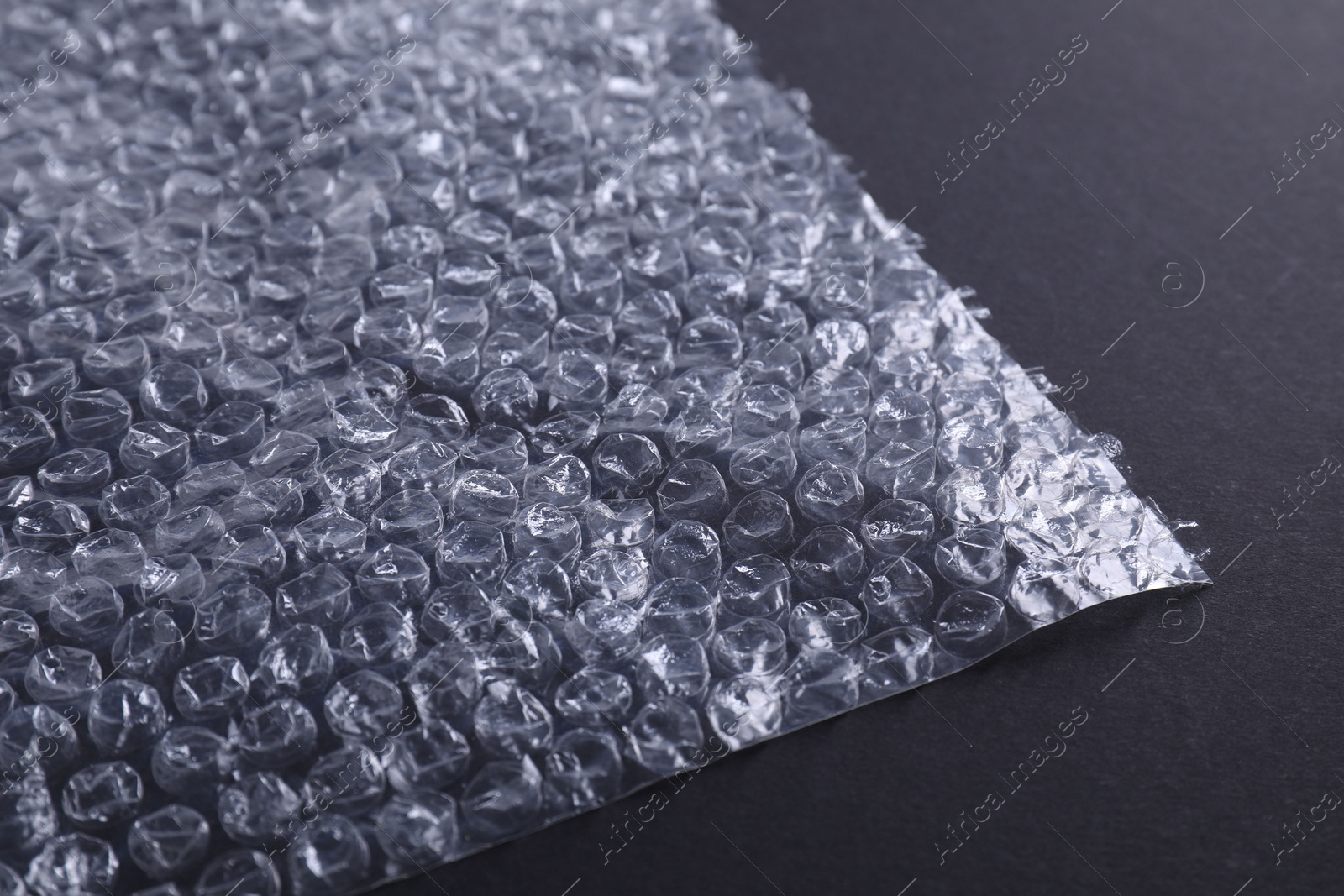 Photo of Transparent bubble wrap on black background, closeup