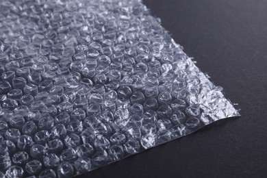 Photo of Transparent bubble wrap on black background, closeup