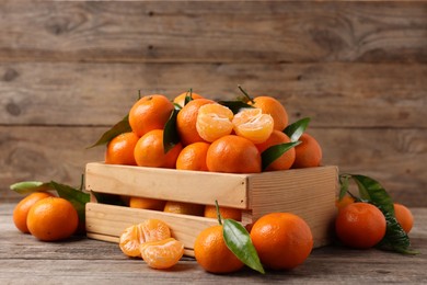 Photo of Delicious tangerines with leaves on wooden table