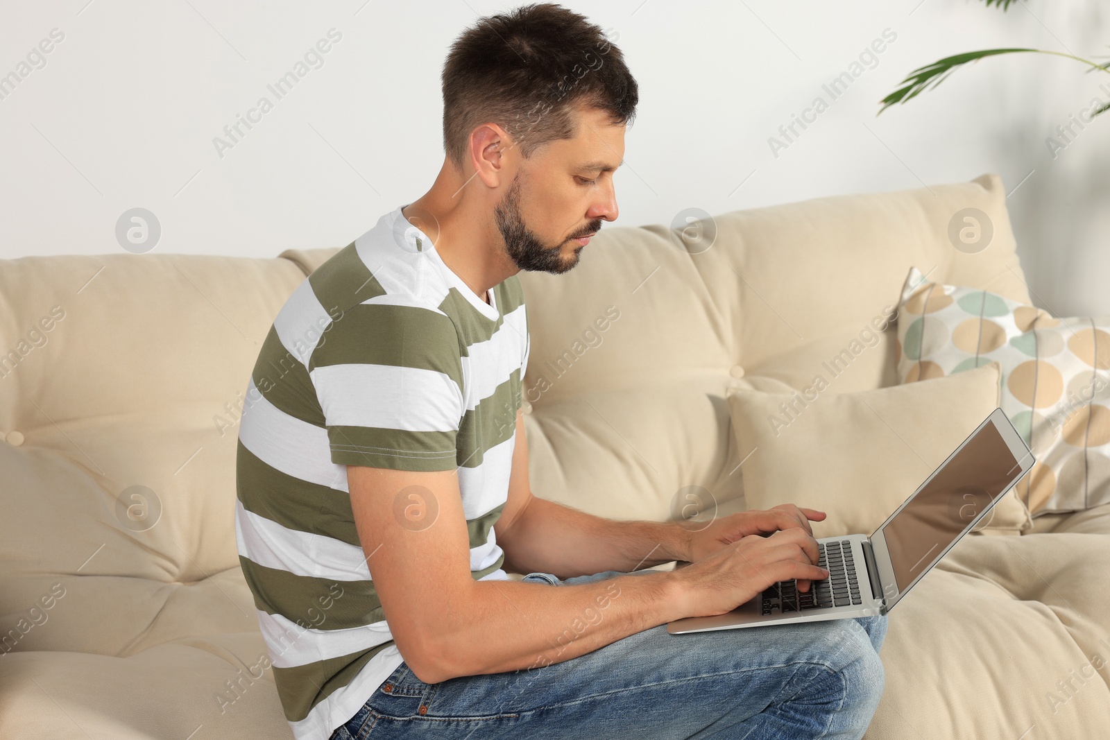 Photo of Man with poor posture using laptop on sofa at home