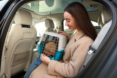 Smiling woman with pet carrier travelling with her dog by car