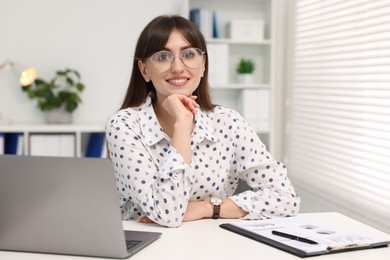 Portrait of smiling secretary at table in office