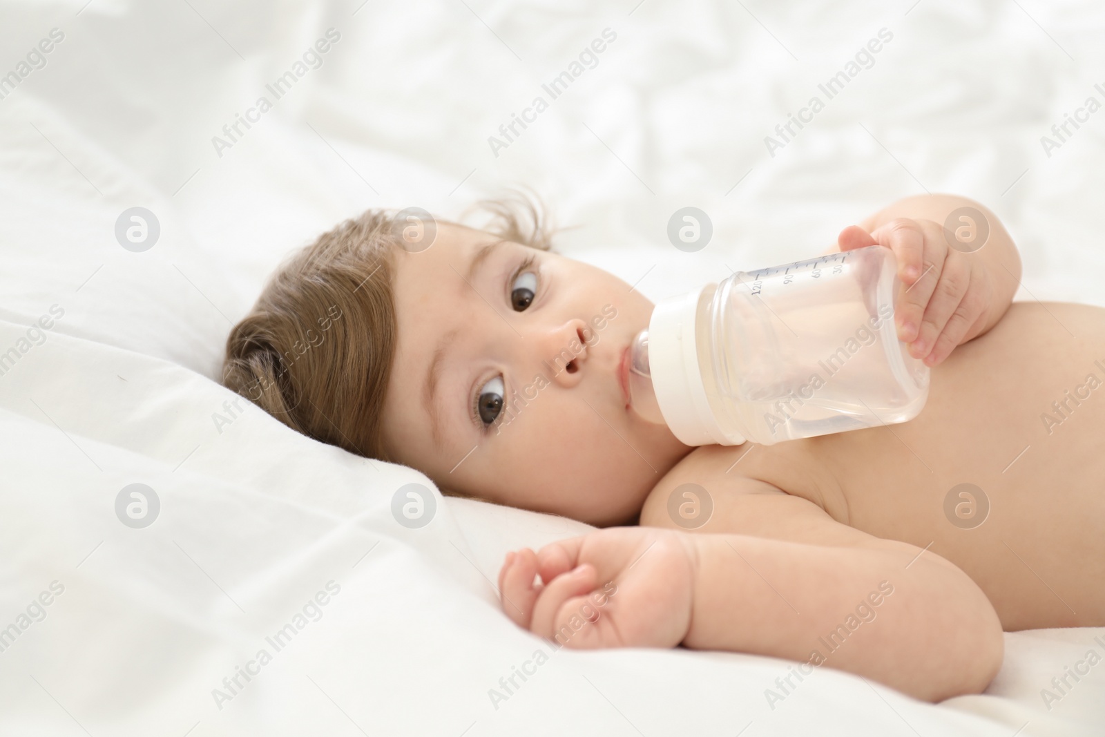 Photo of Cute little baby with bottle on bed