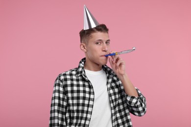 Photo of Young man in party hat with blower on pink background