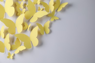 Photo of Yellow paper butterflies on light grey background, top view. Space for text