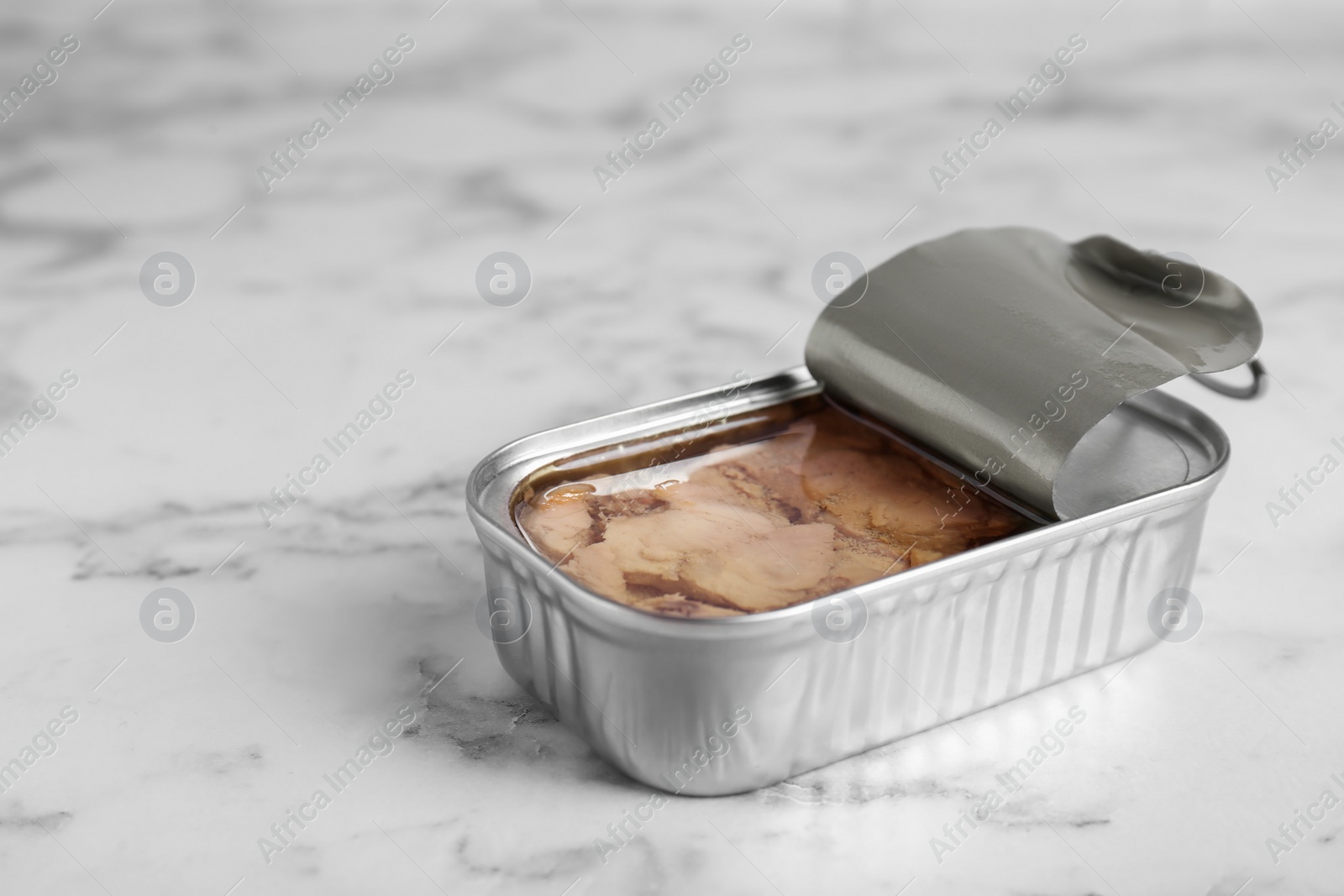 Photo of Open tin can of tasty cod liver on white marble table, closeup. Space for text