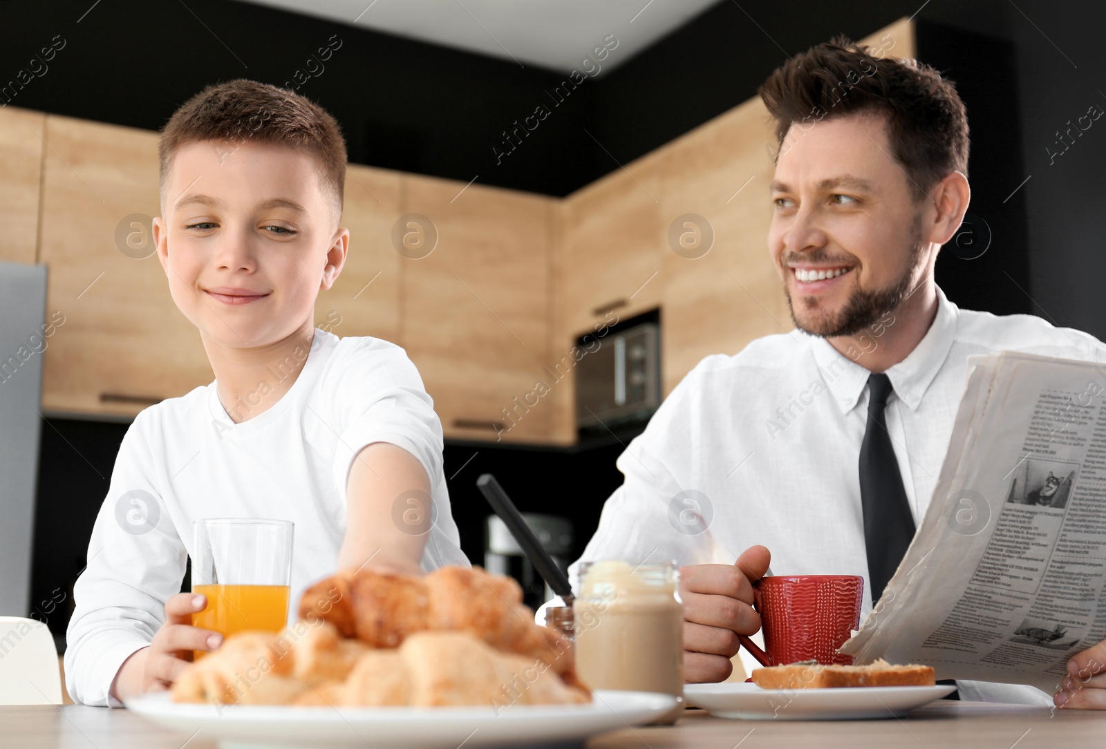 Photo of Dad and son having breakfast together in kitchen