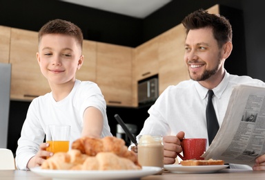 Dad and son having breakfast together in kitchen