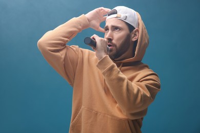 Singer with microphone rapping on light blue background