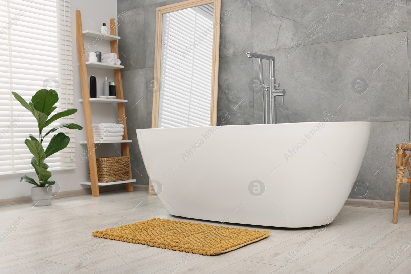 Photo of Stylish bathroom interior with soft yellow bath mat and tub