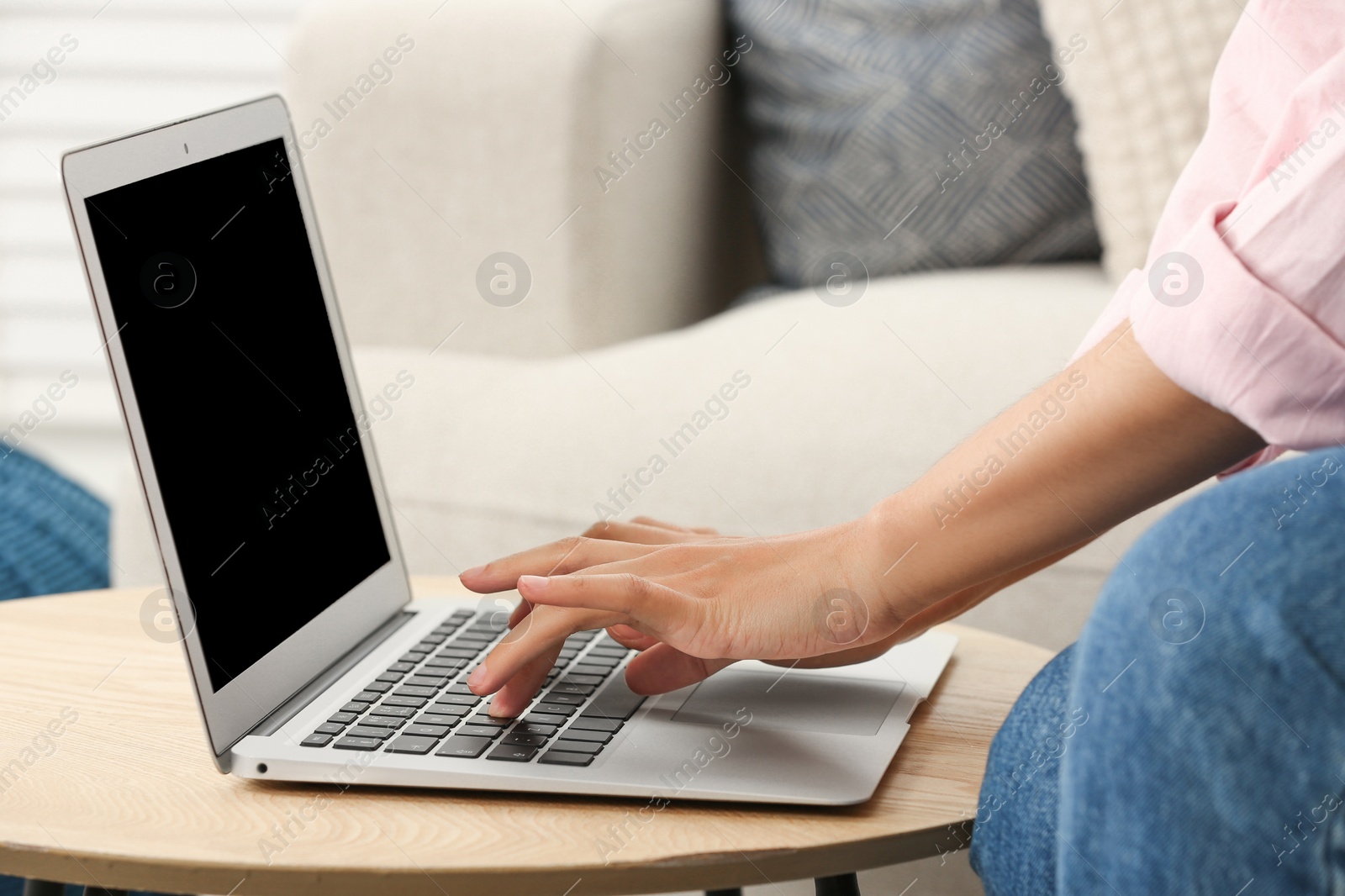 Photo of African American woman typing on laptop at table indoors, closeup