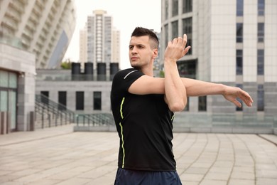 Photo of Young man stretching before morning fitness outdoors