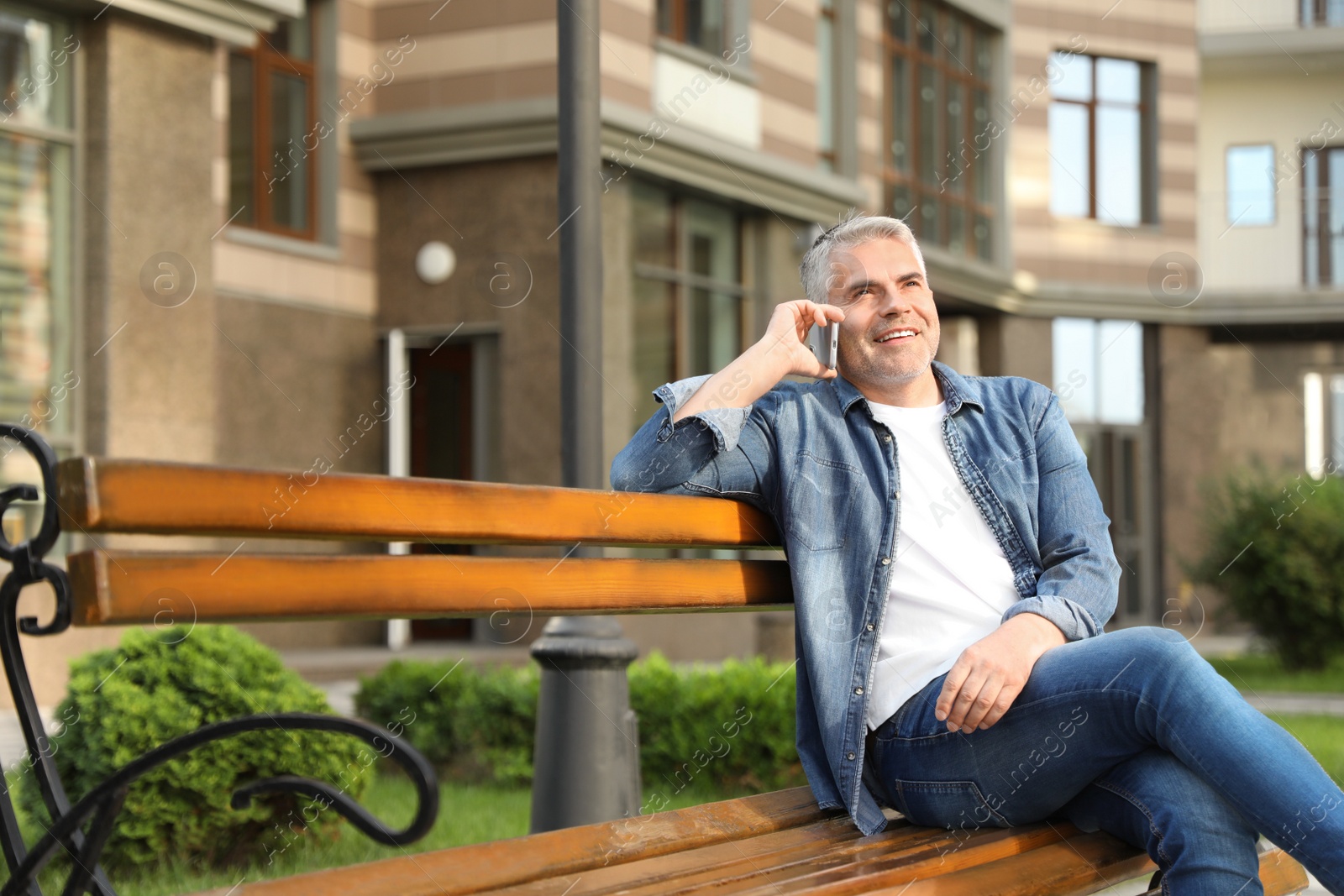 Photo of Handsome mature man talking on phone in city. Space for text