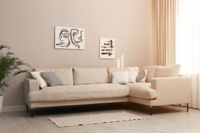 Stylish living room interior with modern comfortable sofa, plant and pictures