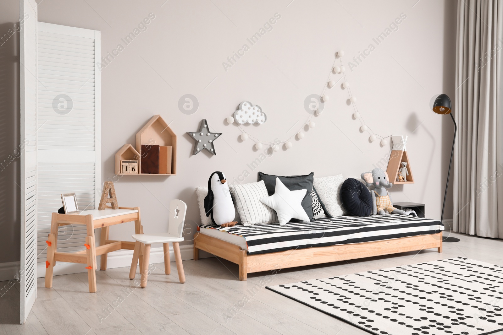 Photo of Cute kids room with stylish comfortable floor bed and toys. Montessori interior