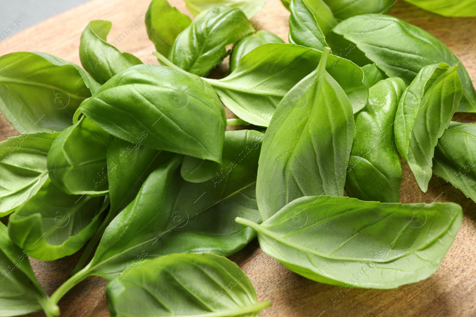 Photo of Fresh basil leaves on wooden table, closeup