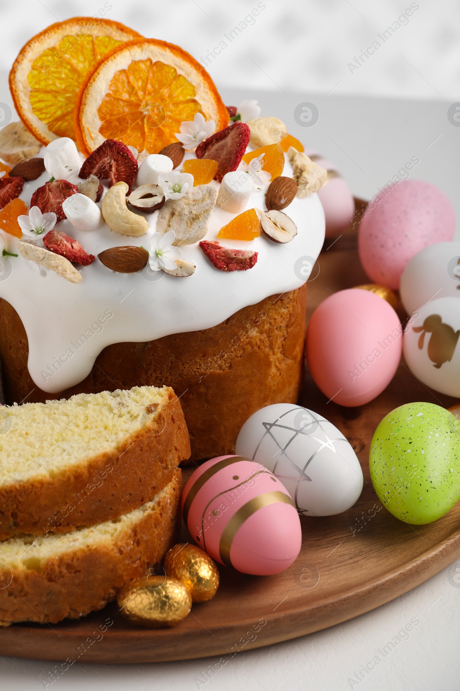 Photo of Traditional Easter cake with dried fruits and painted eggs on white table, closeup