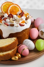 Traditional Easter cake with dried fruits and painted eggs on white table, closeup