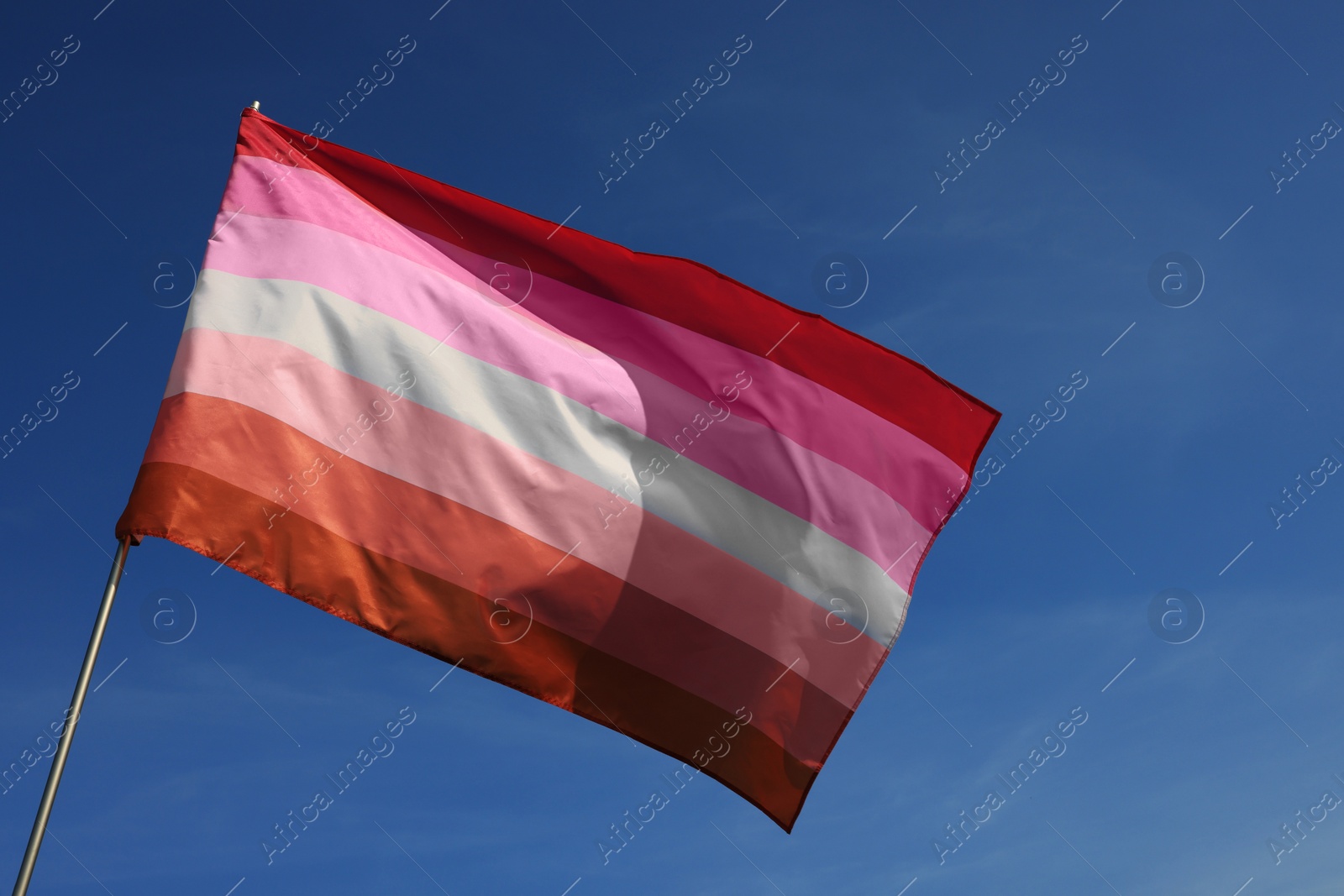 Photo of Bright lesbian flag fluttering against blue sky