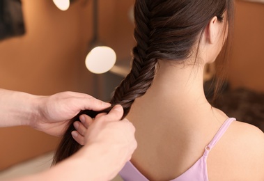 Professional hairdresser working with client in beauty salon, closeup