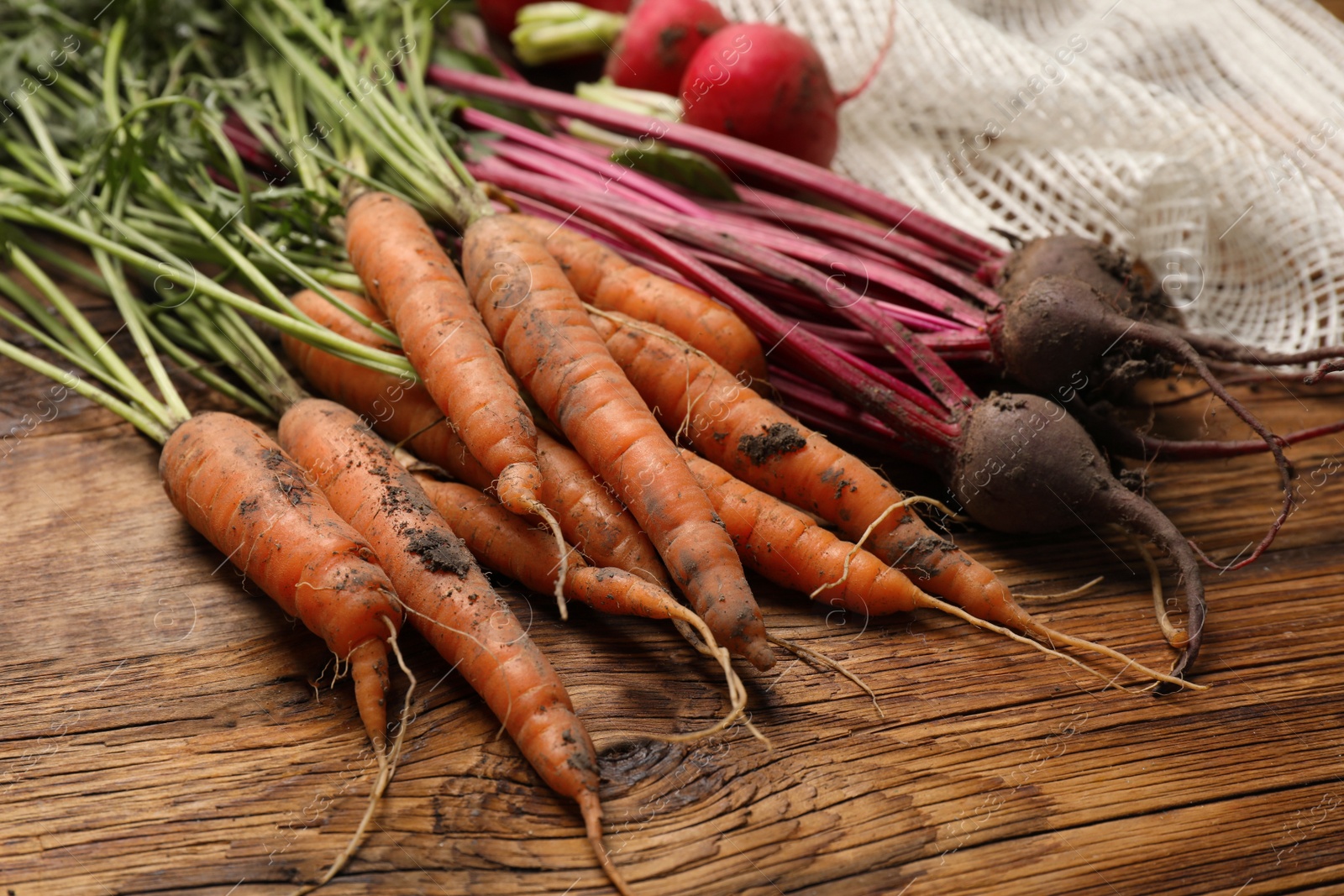 Photo of Different fresh vegetables and net bag on wooden table