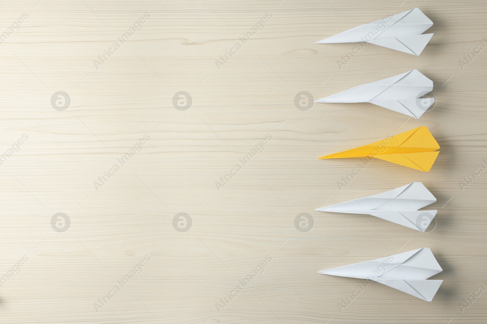 Photo of Handmade colorful paper planes on beige wooden table, flat lay and space for text. Uniqueness concept