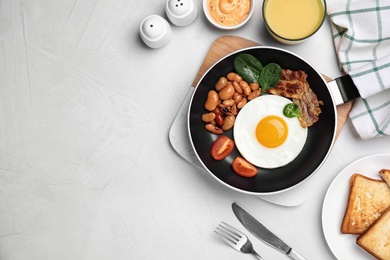 Tasty breakfast with fried egg, beans and bacon on white table, flat lay. Space for text