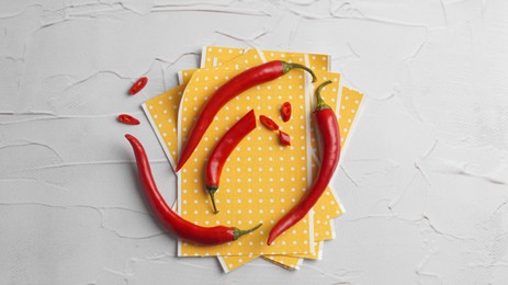 Pepper plasters and chili on white textured table, flat lay