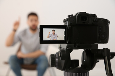 Young blogger recording video indoors, focus on camera screen