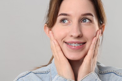 Portrait of smiling woman with dental braces on grey background