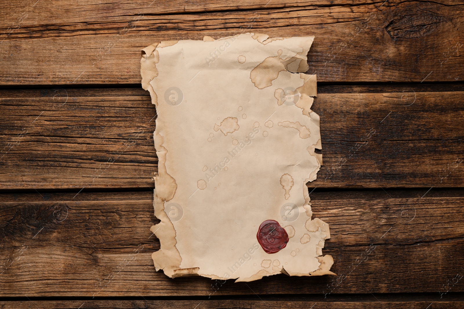 Photo of Sheet of old parchment paper with wax stamp on wooden table, top view. Space for design