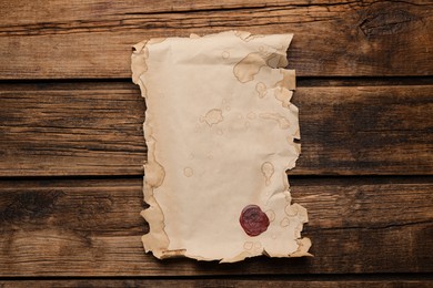 Photo of Sheet of old parchment paper with wax stamp on wooden table, top view. Space for design