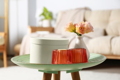 Photo of Box, candles and beautiful flowers on side table at home