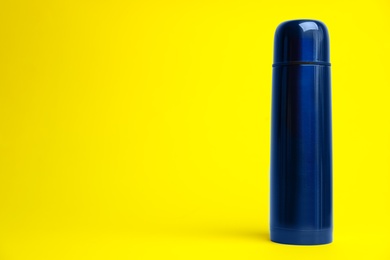 Photo of Stylish thermo bottle on yellow background, space for text