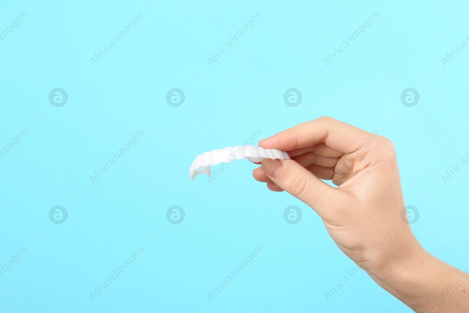 Photo of Woman holding teeth cover on color background. Space for text