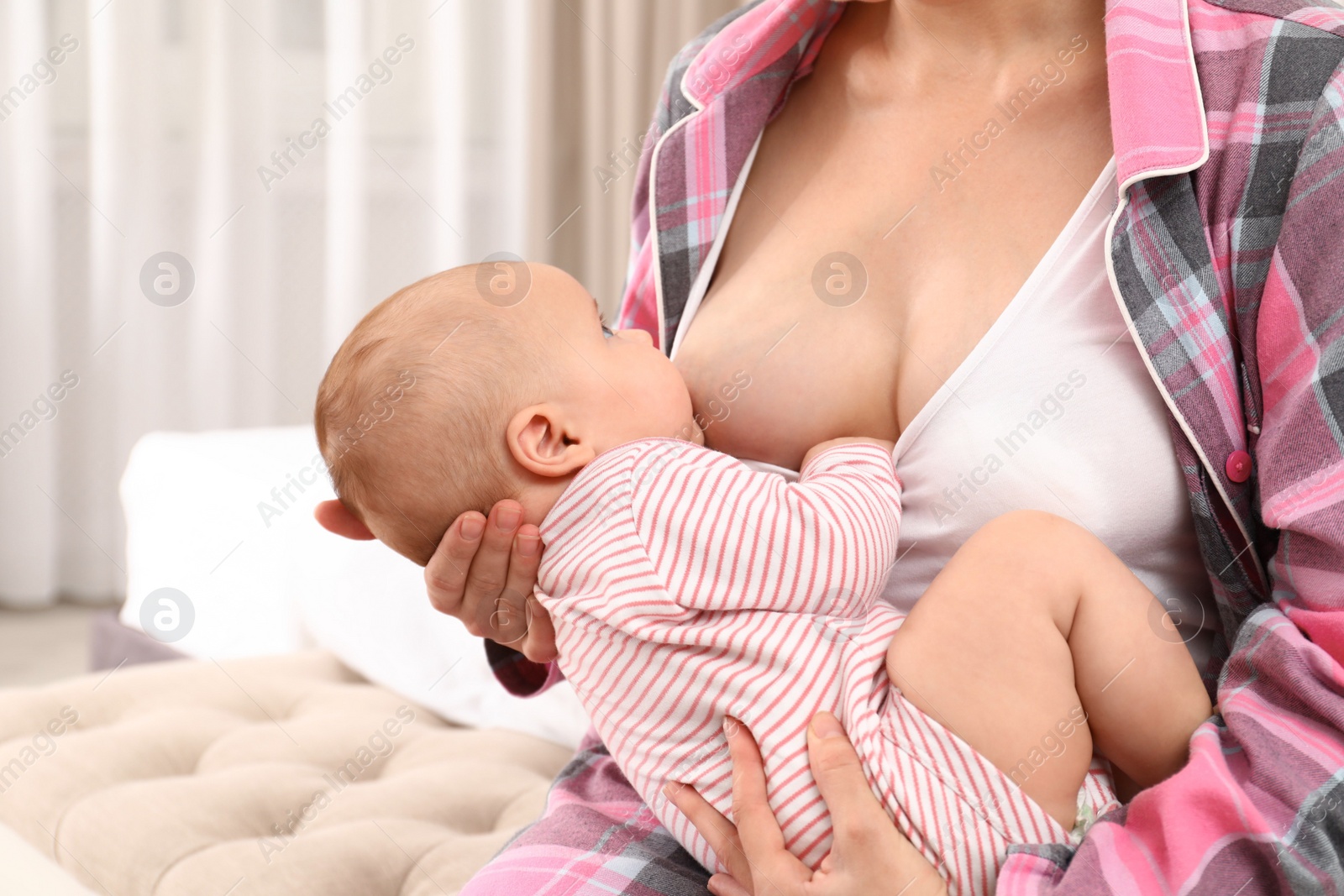 Photo of Young woman breastfeeding her little baby at home