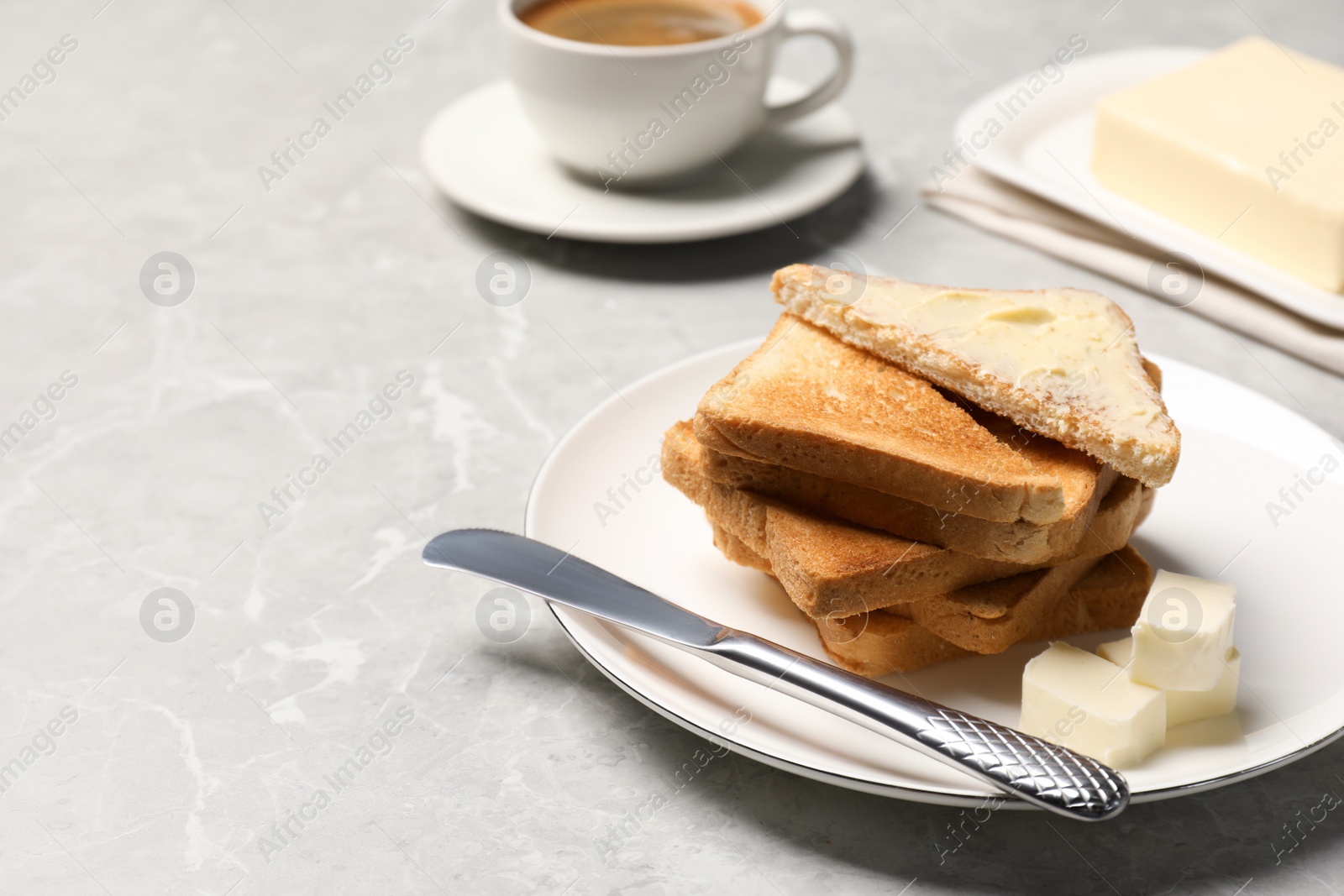 Photo of Tasty toasts with butter served on grey marble table. Space for text