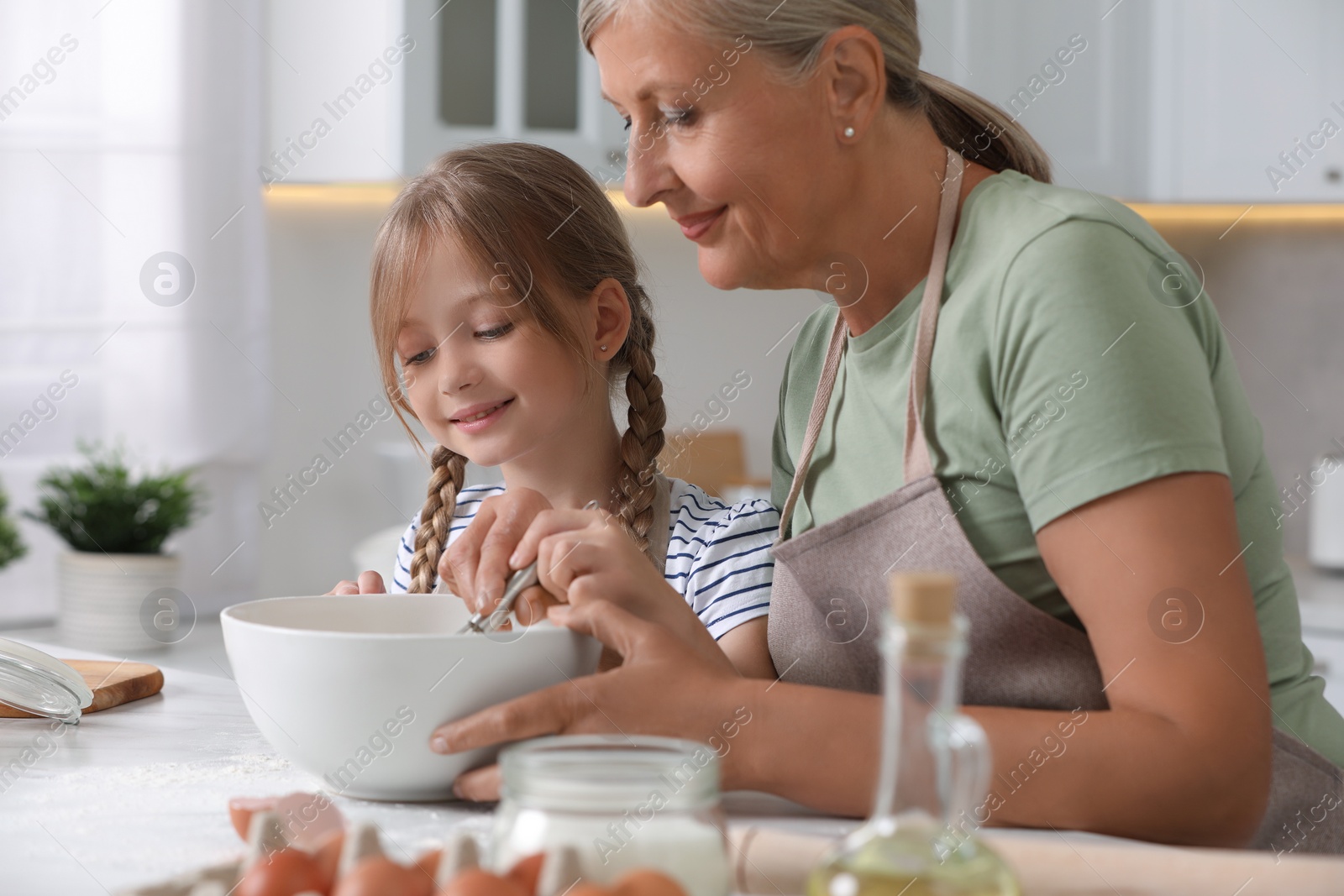 Photo of Happy grandmother with her granddaughter cooking together in kitchen