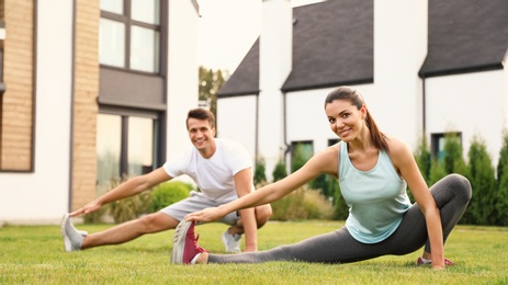 Sporty couple practicing morning yoga at backyard. Healthy lifestyle