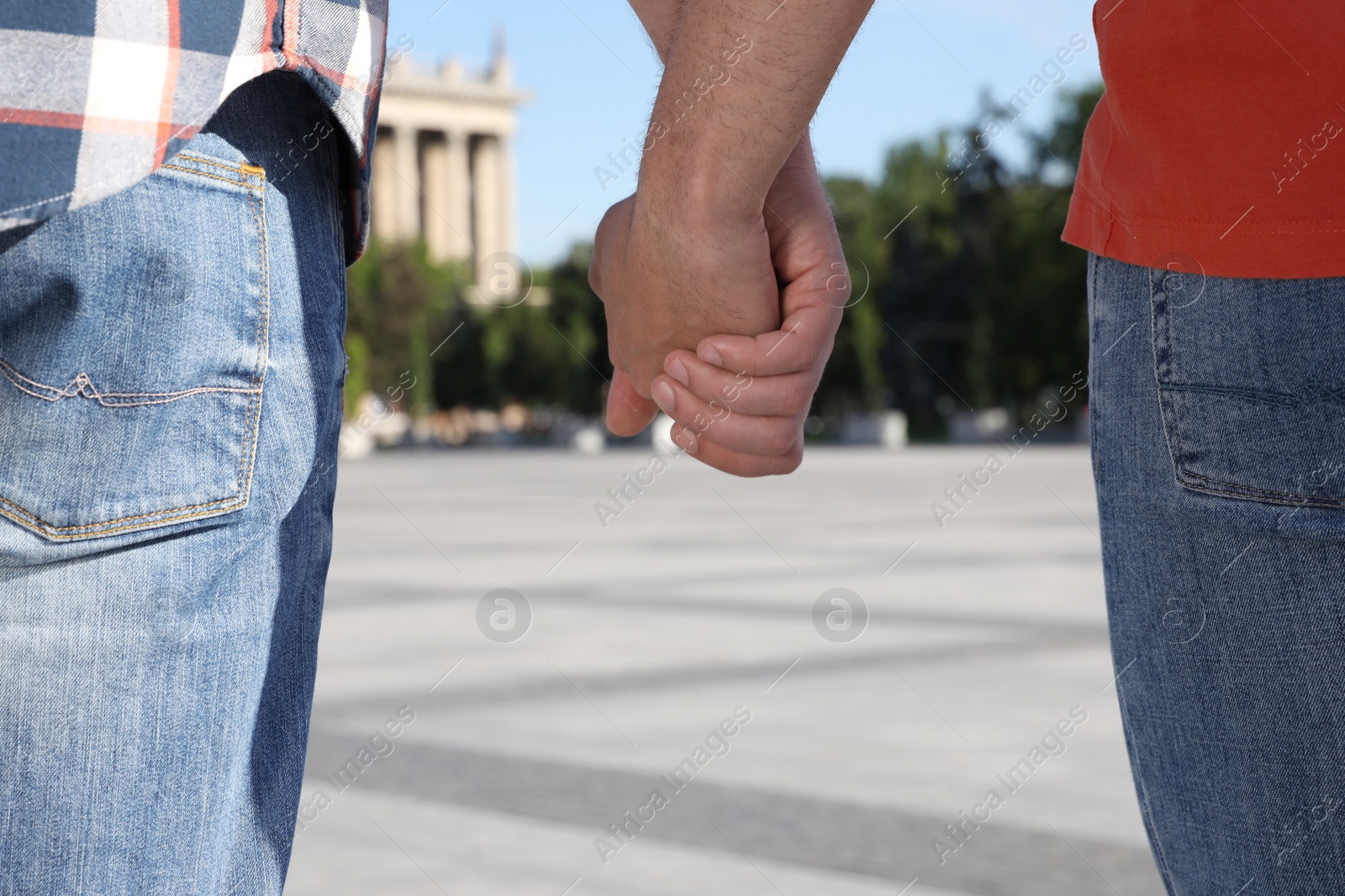 Photo of Gay couple holding hands together outdoors on sunny day, closeup