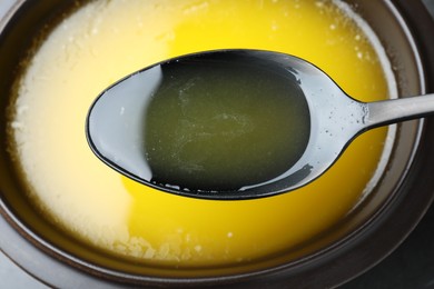 Photo of Spoon of clarified butter over bowl, closeup