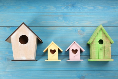 Photo of Collection of handmade bird houses on light blue wooden background, flat lay