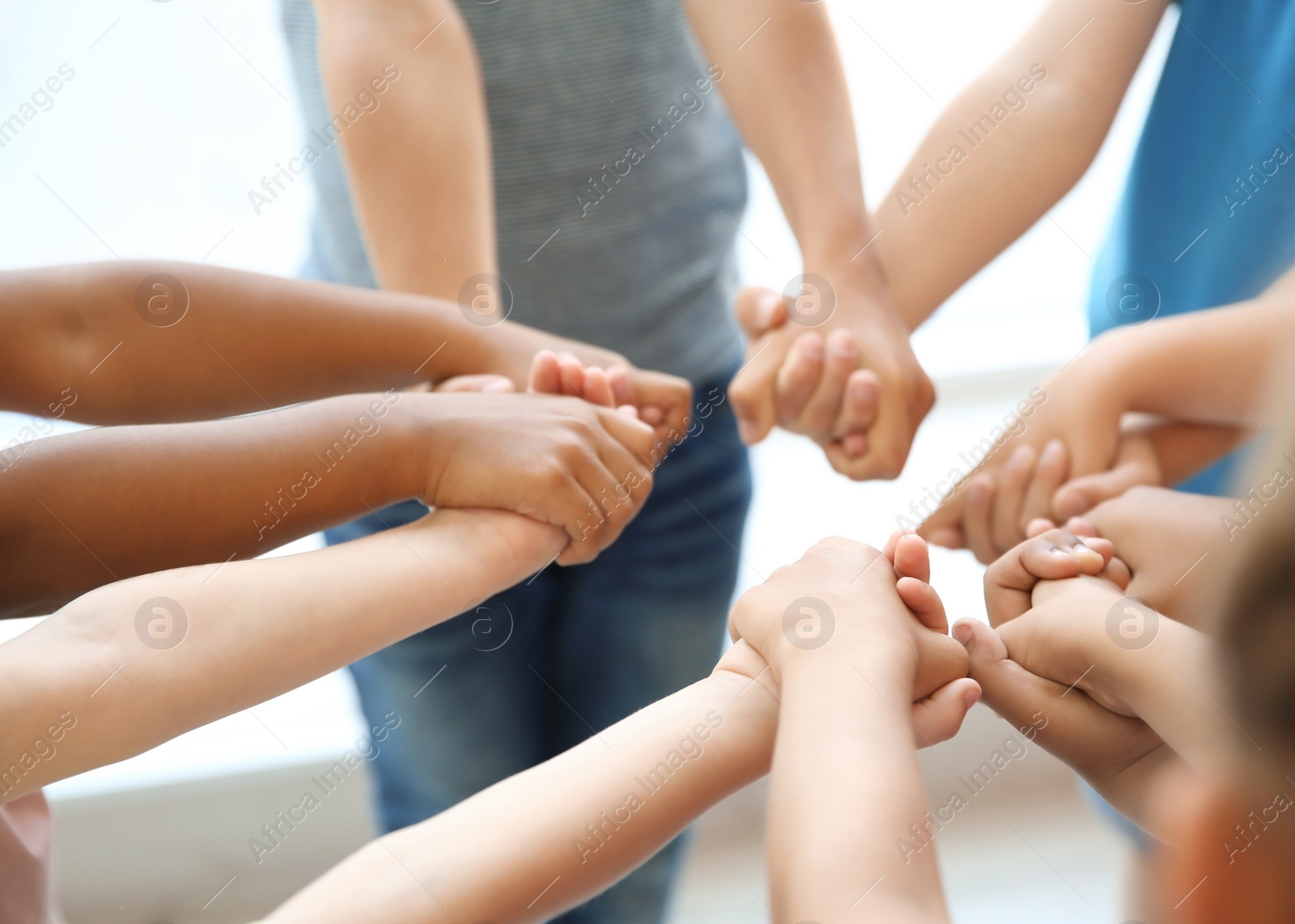 Photo of Little children holding their hands together on light background. Unity concept