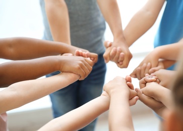 Photo of Little children holding their hands together on light background. Unity concept