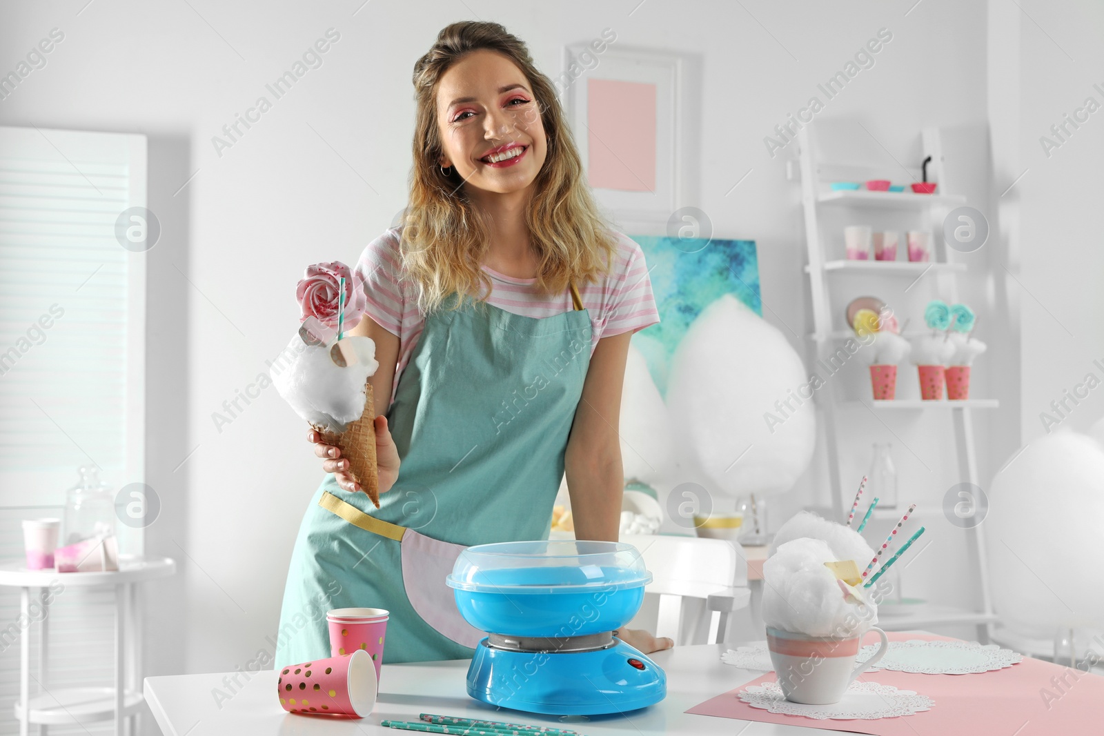 Photo of Young woman with cotton candy dessert at table