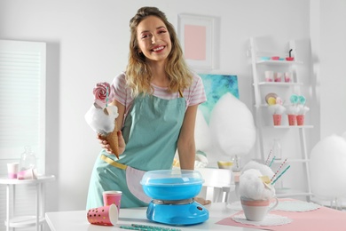 Young woman with cotton candy dessert at table