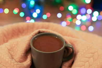 Photo of Cup of delicious hot cocoa wrapped in light cloth