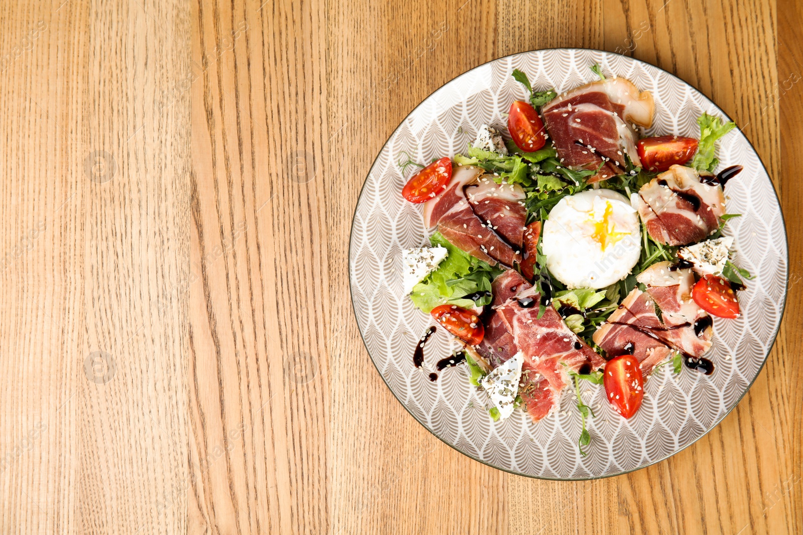 Photo of Delicious prosciutto salad with vegetables served on wooden table, top view. Space for text